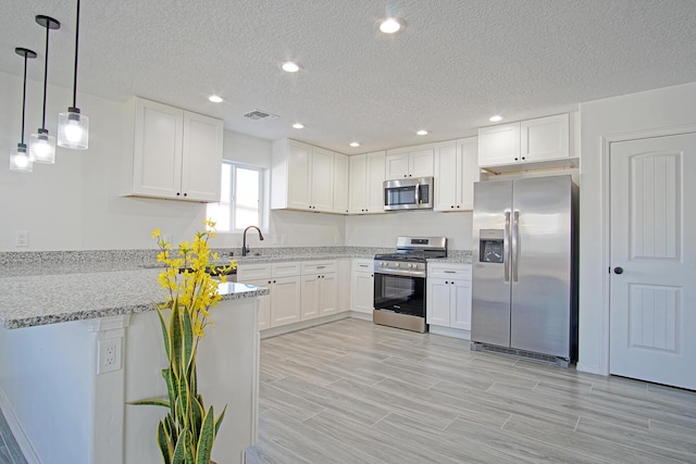 kitchen with light stone counters, white cabinetry, stainless steel appliances, and hanging light fixtures