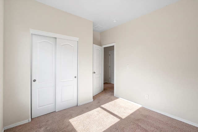 unfurnished bedroom with light carpet and a closet