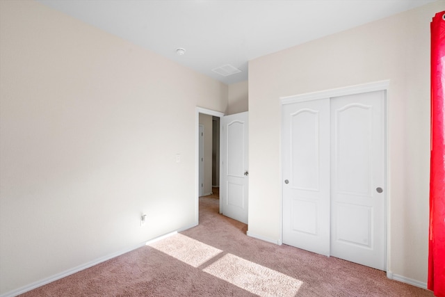 unfurnished bedroom with light colored carpet and a closet