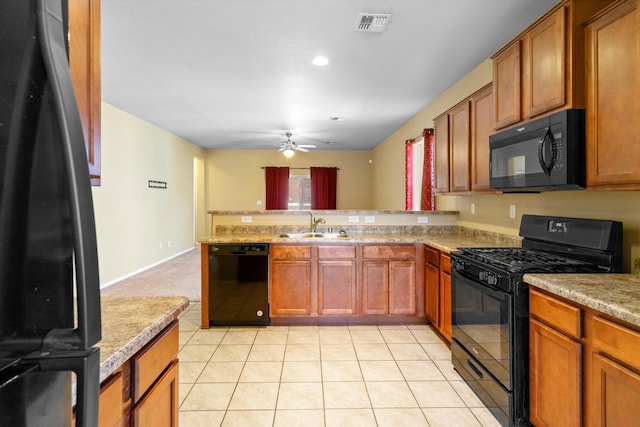 kitchen with light stone countertops, black appliances, sink, kitchen peninsula, and light tile patterned flooring