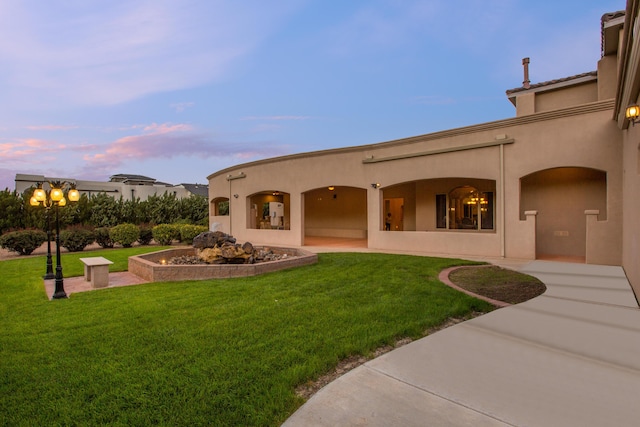 back house at dusk featuring a patio area and a yard