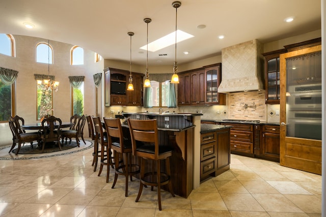 kitchen with premium range hood, light tile patterned floors, decorative backsplash, a kitchen breakfast bar, and a center island