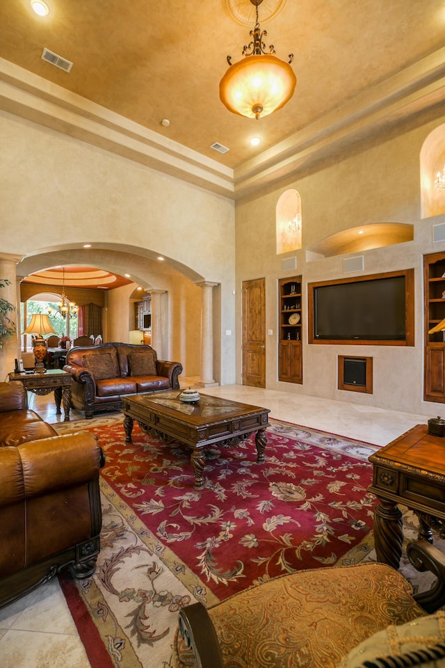 tiled living room with ornate columns, a high ceiling, and built in shelves