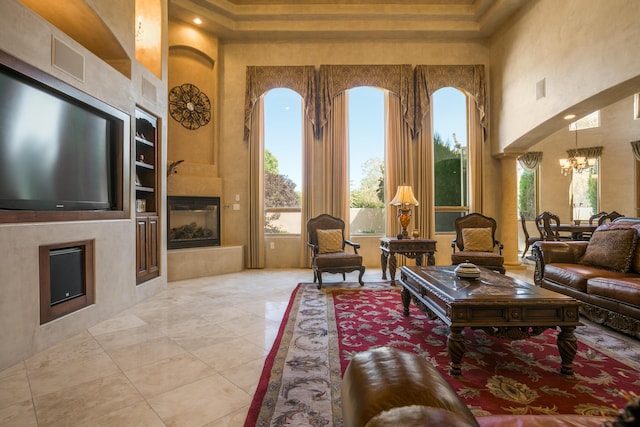 living room with built in features, a towering ceiling, and a notable chandelier