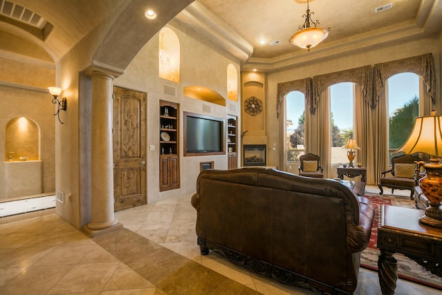 living room featuring ornate columns, built in features, and a towering ceiling