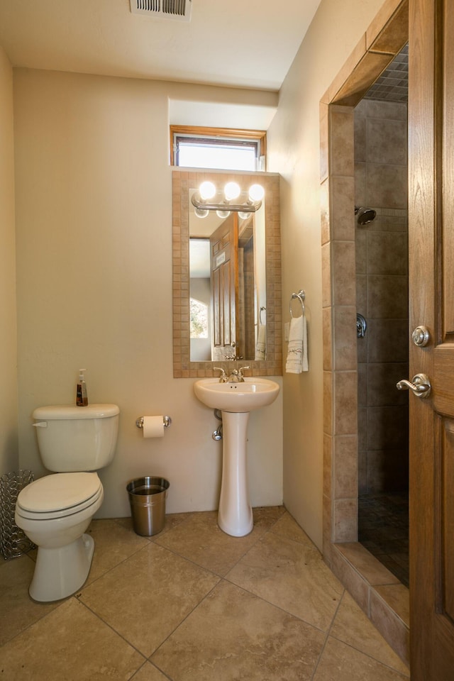 bathroom featuring toilet, tile patterned flooring, and tiled shower