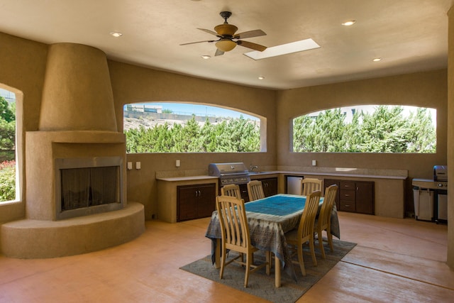 dining area featuring ceiling fan, a skylight, and a fireplace