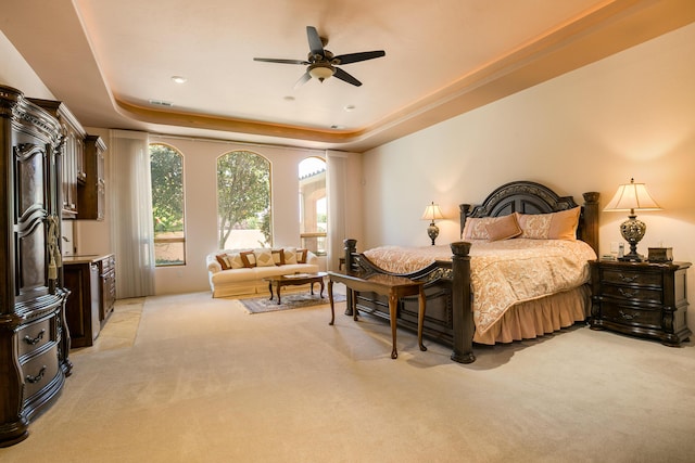 carpeted bedroom featuring ceiling fan and a raised ceiling