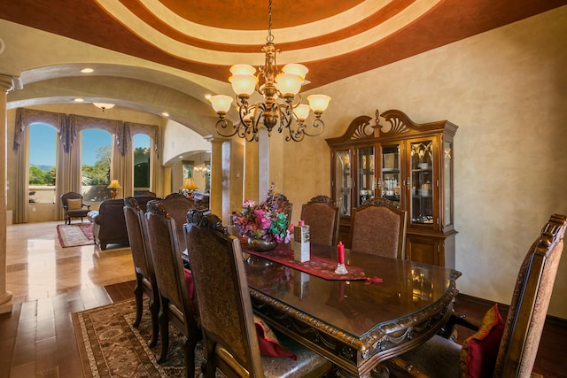 dining area featuring a notable chandelier, hardwood / wood-style flooring, and decorative columns