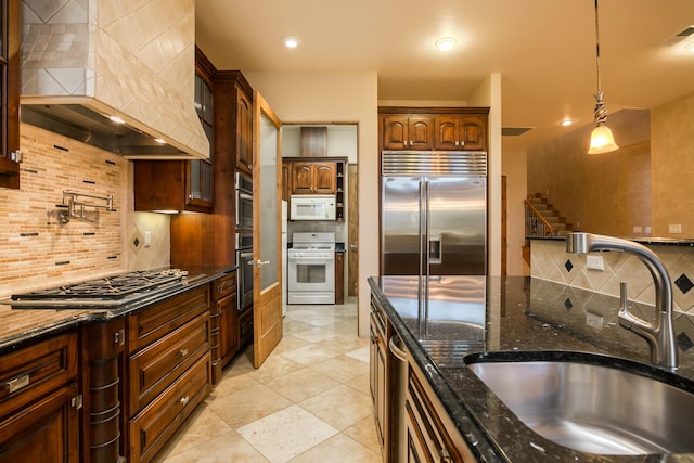 kitchen featuring appliances with stainless steel finishes, custom exhaust hood, tasteful backsplash, sink, and hanging light fixtures