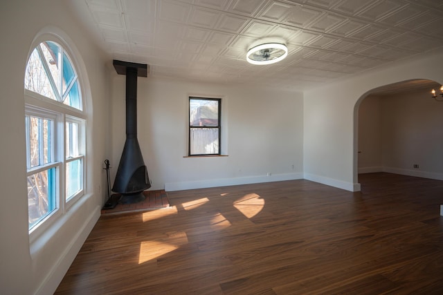 unfurnished room featuring dark wood-type flooring and a wood stove