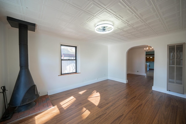 unfurnished room featuring a wood stove and dark hardwood / wood-style floors