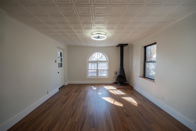 empty room featuring dark wood-type flooring and a wood stove