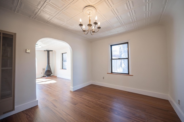 unfurnished room with a wood stove, dark hardwood / wood-style flooring, and an inviting chandelier