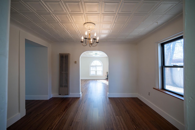 unfurnished dining area with dark wood-type flooring and an inviting chandelier