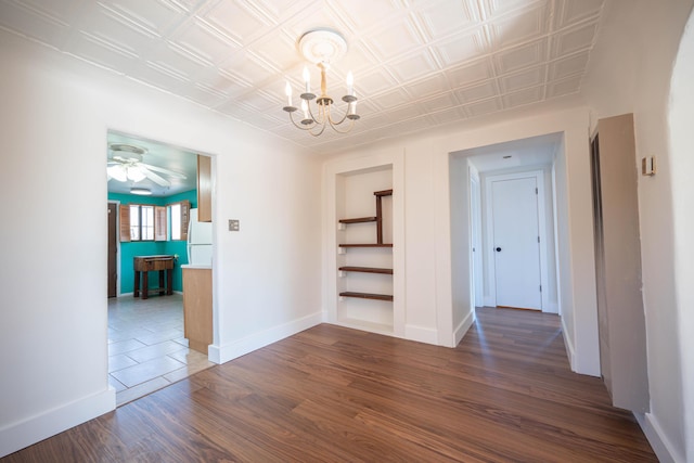 spare room with dark hardwood / wood-style flooring and ceiling fan with notable chandelier