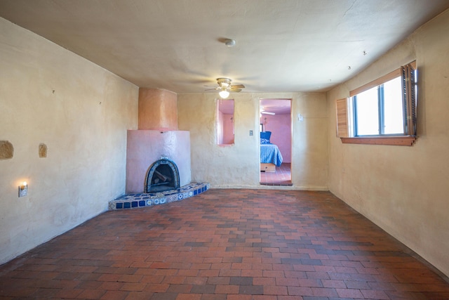 unfurnished living room featuring ceiling fan and a large fireplace