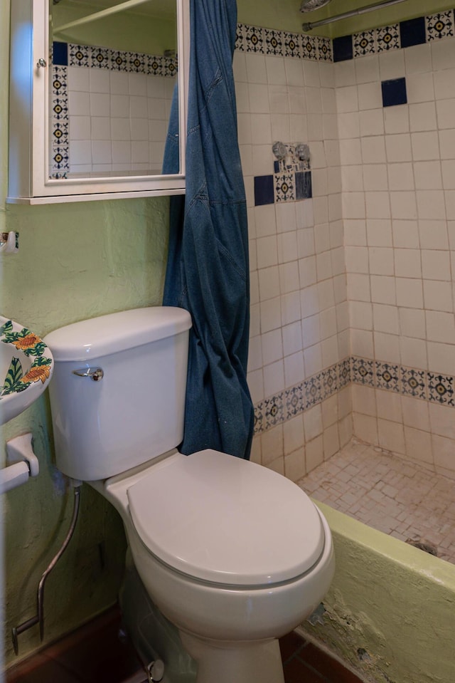 bathroom featuring toilet and a tile shower