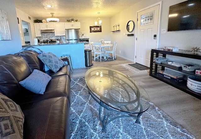 living room featuring hardwood / wood-style flooring, an inviting chandelier, and a textured ceiling