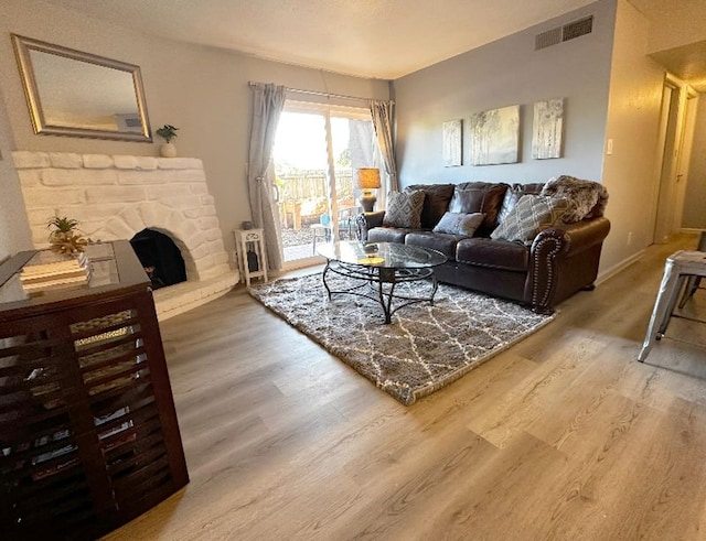 living room featuring a stone fireplace and hardwood / wood-style floors