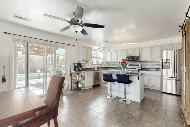 kitchen with a wealth of natural light, a center island, sink, and stainless steel dishwasher