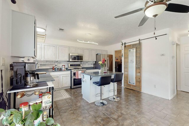 kitchen featuring plenty of natural light, a barn door, ceiling fan, and a center island