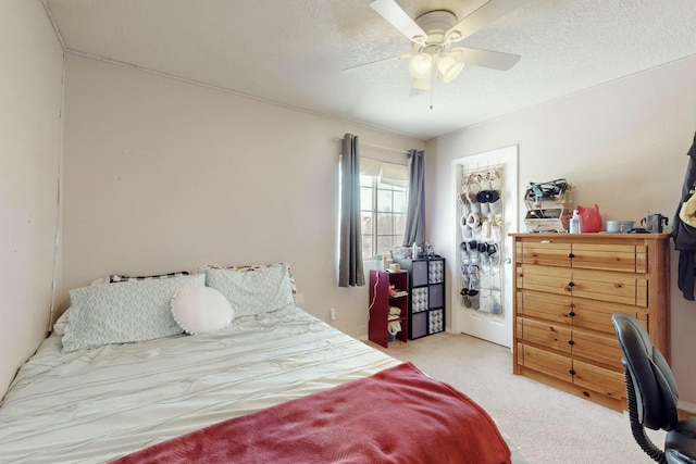 bedroom with light carpet, ceiling fan, and a textured ceiling