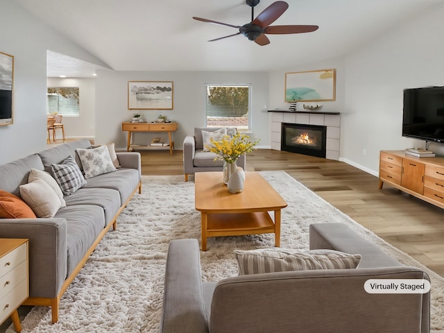 living room featuring ceiling fan, light hardwood / wood-style flooring, a fireplace, and lofted ceiling