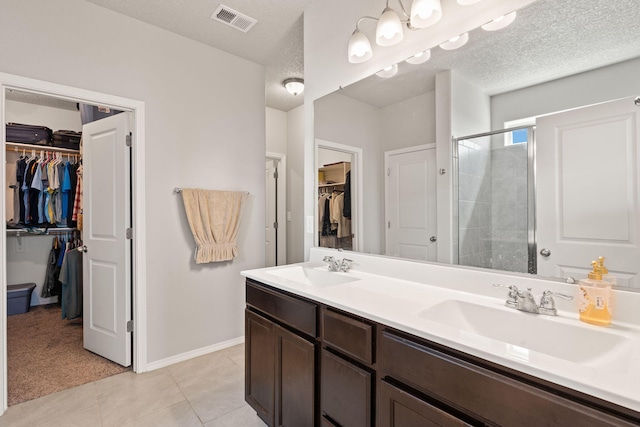 bathroom featuring an enclosed shower, vanity, tile patterned flooring, and a textured ceiling