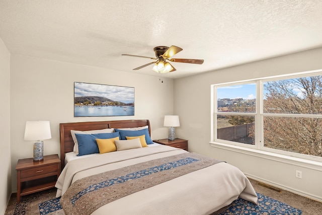 bedroom with a textured ceiling, multiple windows, a ceiling fan, and baseboards