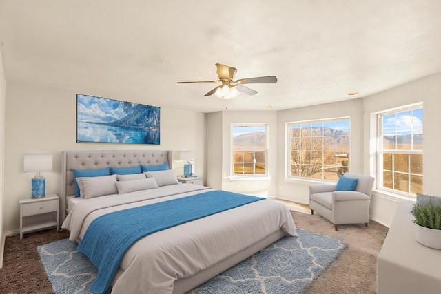 carpeted bedroom featuring a ceiling fan, multiple windows, and baseboards