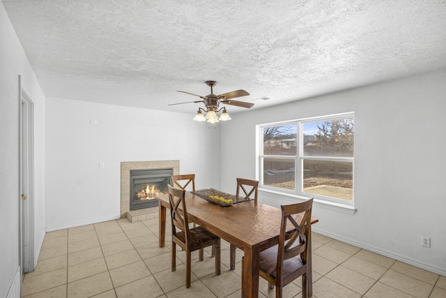 dining area featuring a tile fireplace, visible vents, ceiling fan, and baseboards