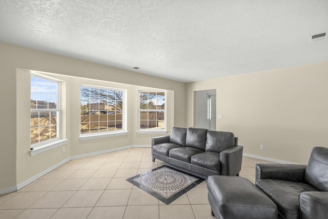 living area with visible vents, a textured ceiling, baseboards, and light tile patterned floors