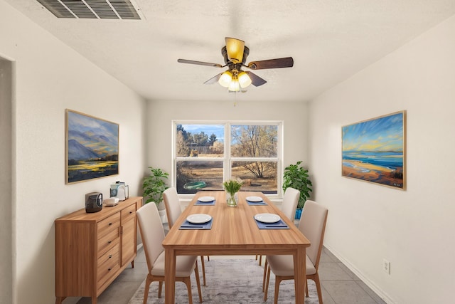 dining area featuring baseboards, visible vents, a ceiling fan, and light tile patterned flooring