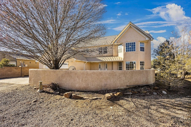 rear view of house featuring a fenced front yard and stucco siding