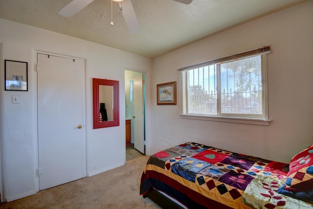 bedroom featuring ceiling fan, light colored carpet, and a textured ceiling