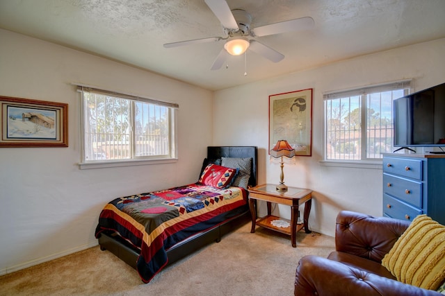 carpeted bedroom featuring ceiling fan and a textured ceiling