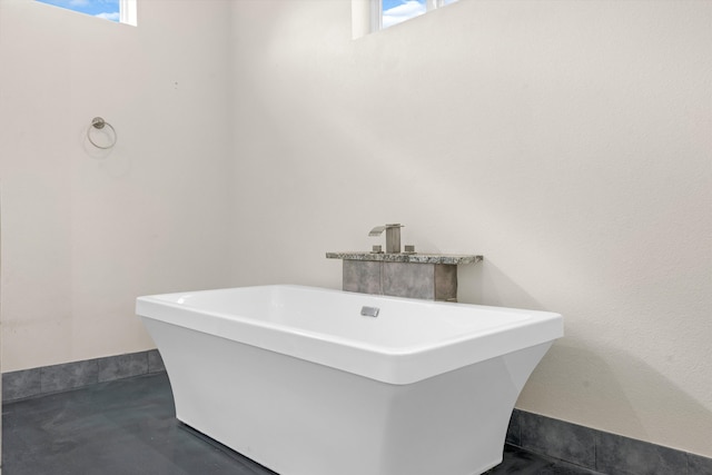 bathroom featuring a tub, plenty of natural light, and concrete flooring