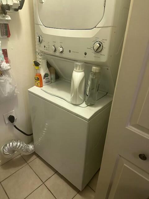 clothes washing area with light tile patterned floors and stacked washer and dryer