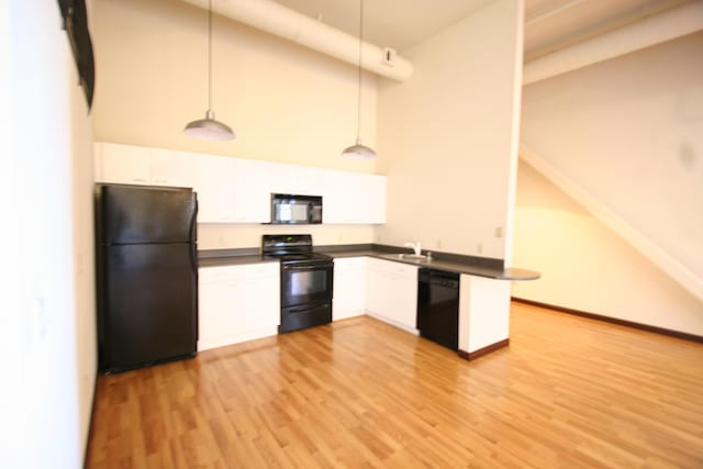 kitchen featuring decorative light fixtures, black appliances, a high ceiling, and white cabinets