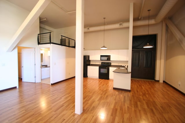 kitchen with decorative light fixtures, white cabinetry, a high ceiling, light hardwood / wood-style floors, and black appliances