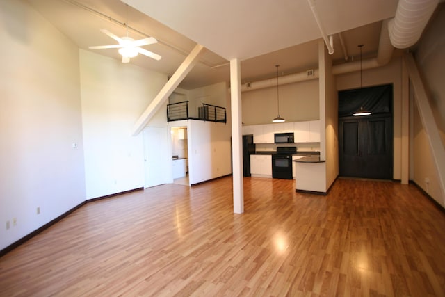 unfurnished living room with hardwood / wood-style floors, a high ceiling, and ceiling fan