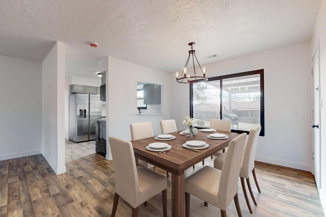 dining space featuring dark wood-type flooring, a chandelier, and a textured ceiling