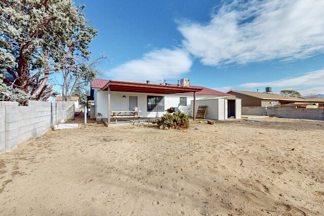 rear view of property with a storage shed