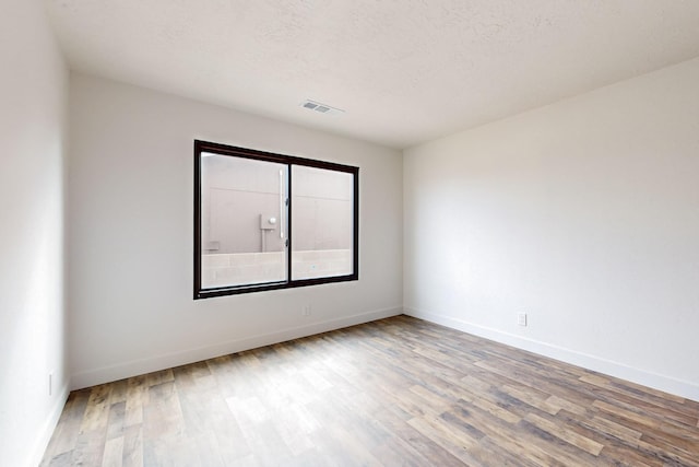 empty room with hardwood / wood-style flooring and a textured ceiling