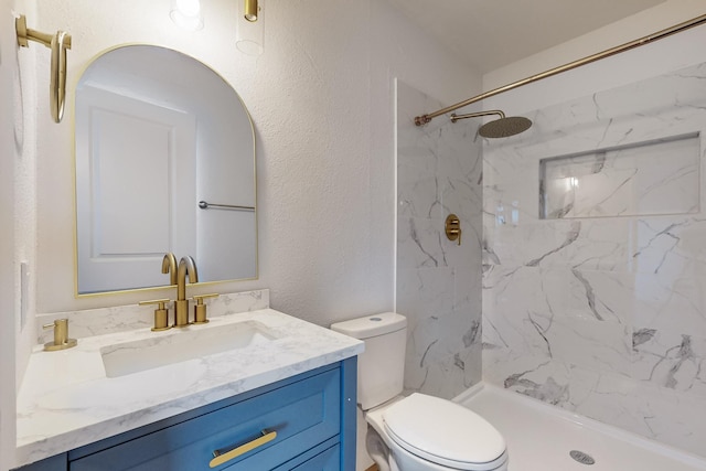 bathroom with vanity, tiled shower, and toilet