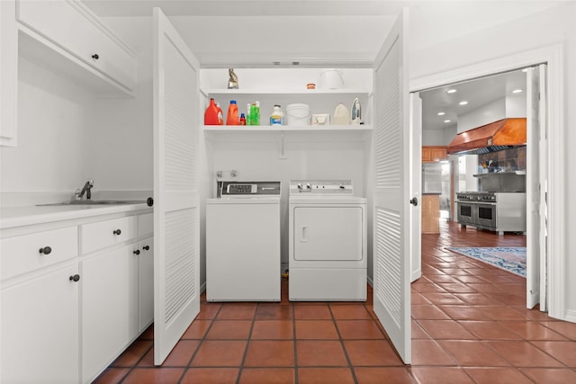 laundry room with dark tile patterned floors, washing machine and clothes dryer, and sink