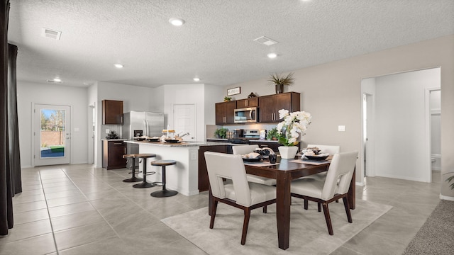 dining area with a textured ceiling and light tile patterned floors