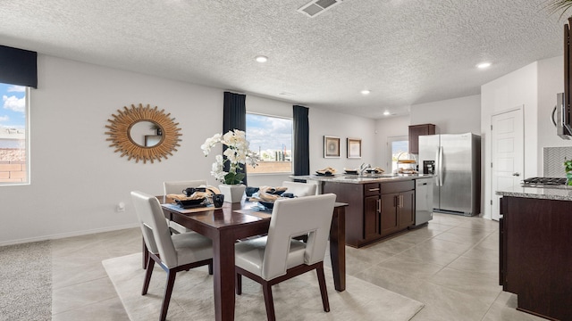 tiled dining area featuring sink, a textured ceiling, and a wealth of natural light