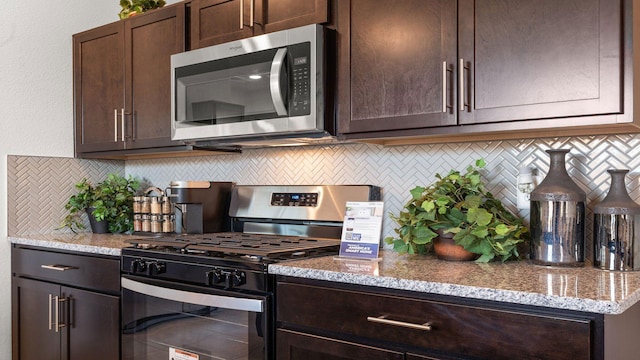 kitchen featuring appliances with stainless steel finishes, light stone counters, dark brown cabinetry, and decorative backsplash